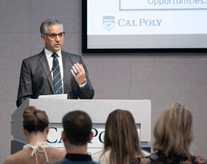 man speaking at podium in front of crowd